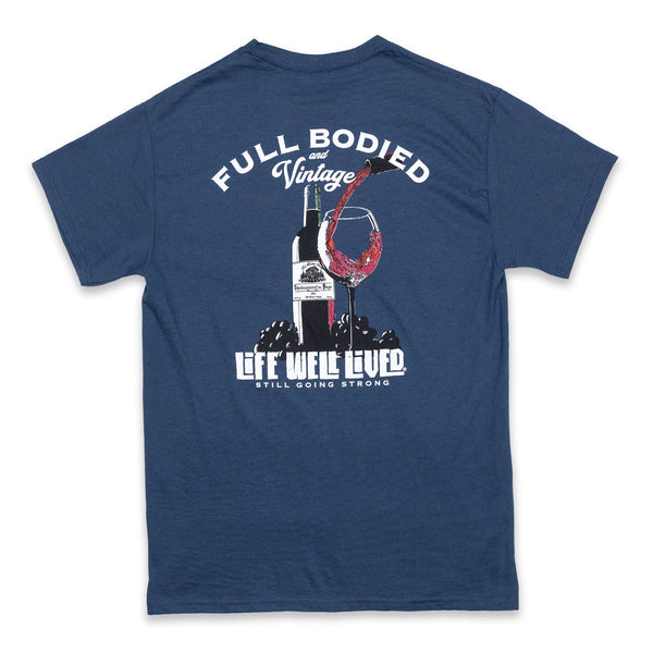 Classic mens back print graphic Tee, depicting a red wine bottle next to a glass of wine being poured, Above the image it reads 'Full Bodied Vintage in white lettering. The Tee is on a blue Dusk colour. Underneath the image it reads 'Life Well Lived, 'still going strong'.