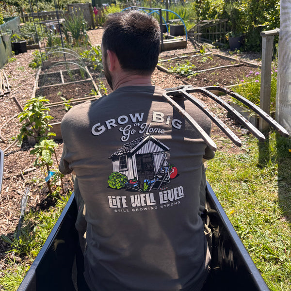 “Grow Bigger gardening T‑Shirt worn outdoors in a natural allotment setting, showing the hand‑drawn design.”