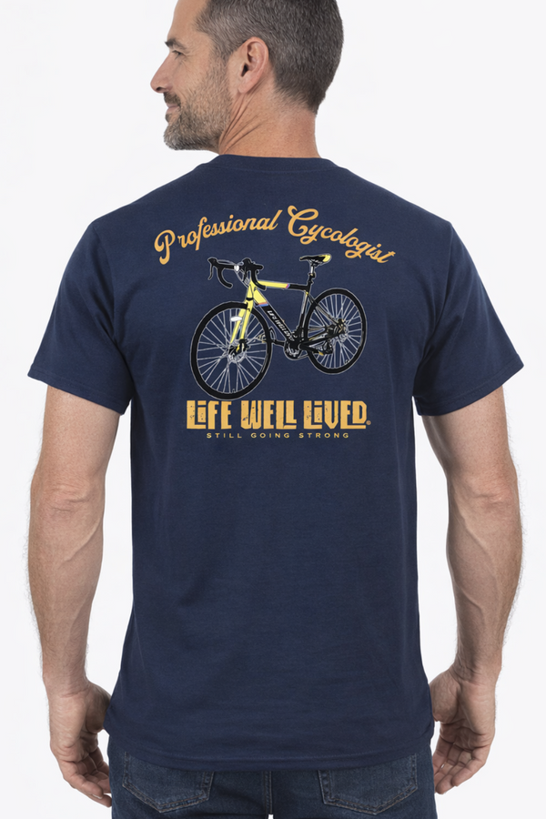 Back view of navy Professional Cycologist cycling T‑shirt featuring yellow road bike graphic with Professional Cycologist text above and Life Well Lived Still Going Strong branding below.