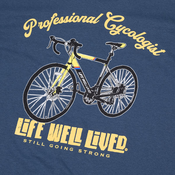 This classic men's back print graphic tee shirt, on Blue dusk colour. Design is of an older style road racer style push bike, above the image of the bike is written 'Professional Cycologist'. Graphics are in a golden yellow colour.