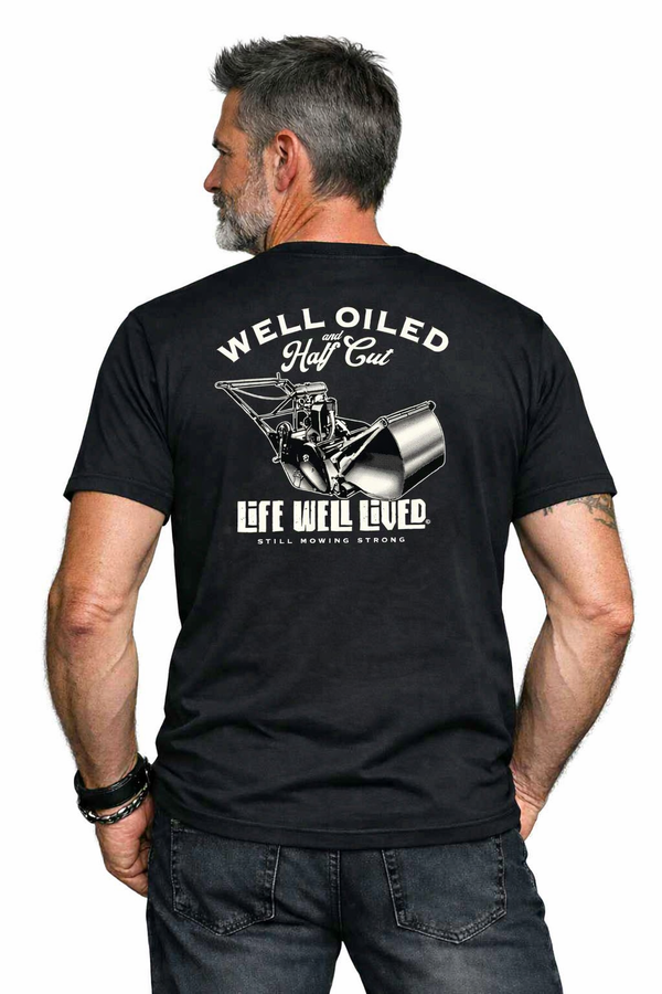 Man wearing the Well Oiled Half Cut black T‑Shirt showing the bold lawnmower back print.