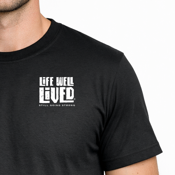 Black t-shirt with 'Life Well Lived' text worn by a person on a white background