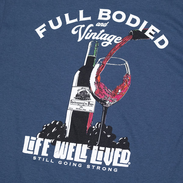 Classic mens back print graphic Tee, depicting a red wine bottle next to a glass of wine being poured, Above the image it reads 'Full Bodied Vintage in white lettering. The Tee is on a blue Dusk colour. Underneath the image it reads 'Life Well Lived, 'still going strong'.