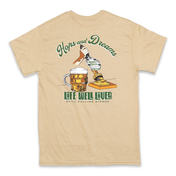 This mens graphic back print Tee shirt, shows an image of a beer pump being pulled, next to the pump is a traditional pint glass full of beer, the beer being pulled is called 'Hoppy Daze'  The strapline above says hops & Dreams, a great t shirt for any beer lover, finished in golden graphics with green lettering on a Tan colour base Tee.
