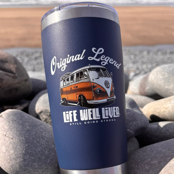 Blue tumbler with a vintage van design on pebbles by the beach