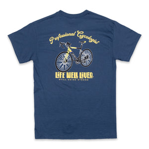 This classic men's back print graphic tee shirt, on Blue dusk colour. Design is of an older style road racer style push bike, above the image of the bike is written 'Professional Cycologist'. Graphics are in a golden yellow colour.