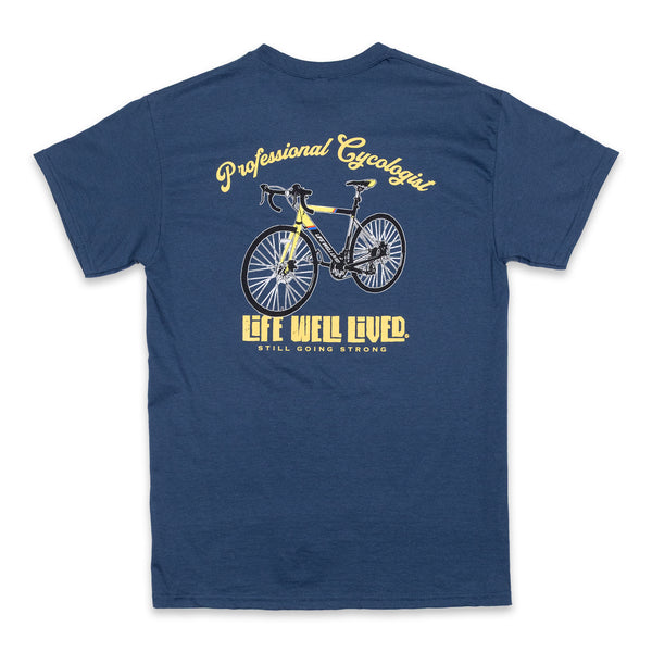 This classic men's back print graphic tee shirt, on Blue dusk colour. Design is of an older style road racer style push bike, above the image of the bike is written 'Professional Cycologist'. Graphics are in a golden yellow colour.