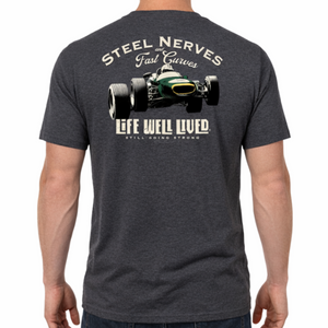 Back view of a male model wearing the dark grey Steel Nerves Formula One T‑Shirt featuring the vintage race car graphic with Steel Nerves and Life Well Lived text.