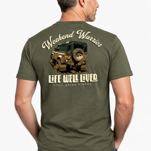 Back view of olive green Weekend Warrior T‑shirt featuring rugged off road 4x4 vehicle graphic with Weekend Warrior text above and Life Well Lived Still Going Strong branding below.